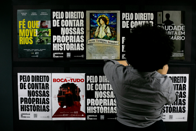 Mural com cartazes sobre direito de contar histórias e filmes exibidos, com mulher de cabelo black power à frente.