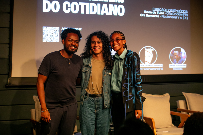 Well Amorim, Lekun Barboni e Rayanna do Nascimento em pé diante da tela do auditório.