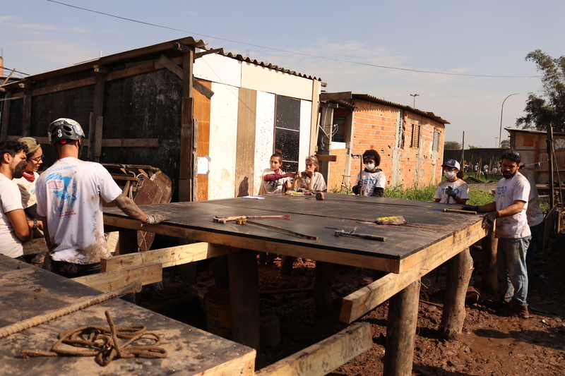Grupo de voluntários construindo o pavimento de uma das casas resilientes do projeto +Lapena Habitar.