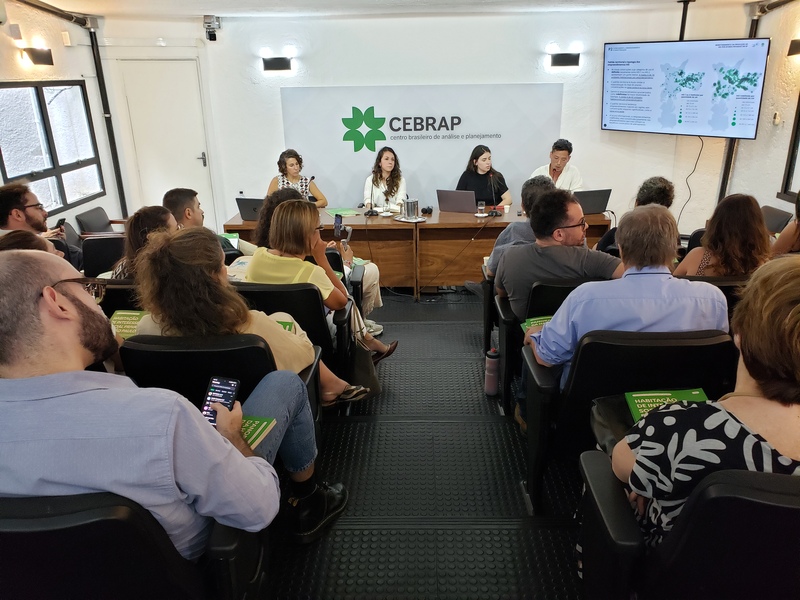 Evento de lançamento do estudo Panorama da Habitação de Interesse Social no auditório do Cebrap, com pesquisadores no palco e plateia segurando exemplares da publicação.