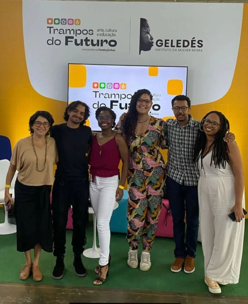 Grupo com Fernanda Nobre, Frances Gonf, Lassalette Jorge, Ariely Tombô, Amauri Eugênio Jr. e Natália Carneiro abraçados em frente ao palco do evento Trampos do Futuro.